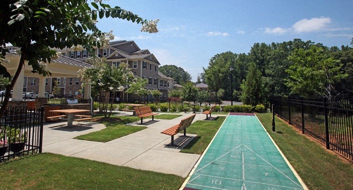 A green running track in a park with benches and trees.