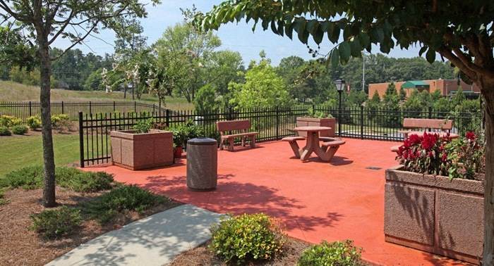 A park with a red surface and a black fence.