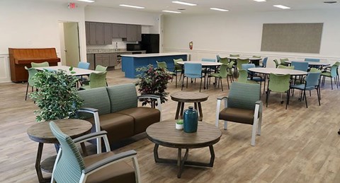 a large living room with tables and chairs and a kitchen