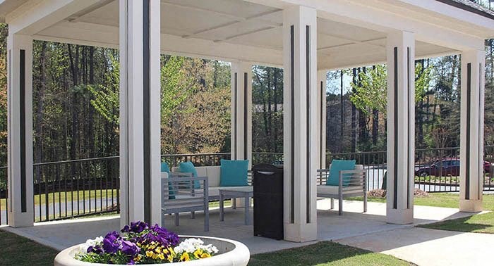 a covered patio with chairs and a table with flowers