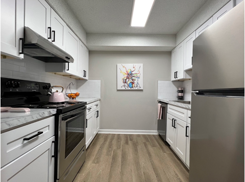 an empty kitchen with stainless steel appliances and white cabinets
