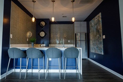 a kitchen with blue chairs in front of a bar with a sink