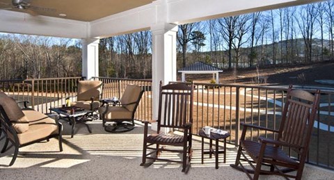 a porch with rocking chairs and a table and a pool