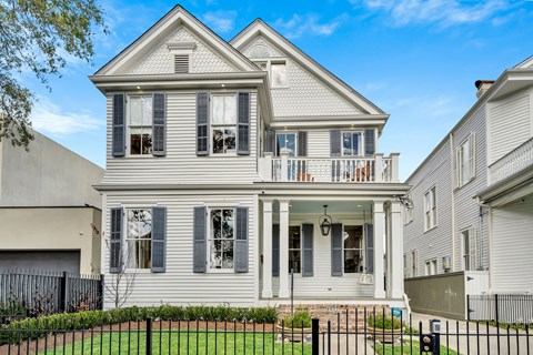 A two-story house with a front porch and a black fence.