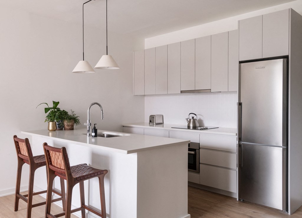 a kitchen with a white counter top and a stainless steel refrigerator