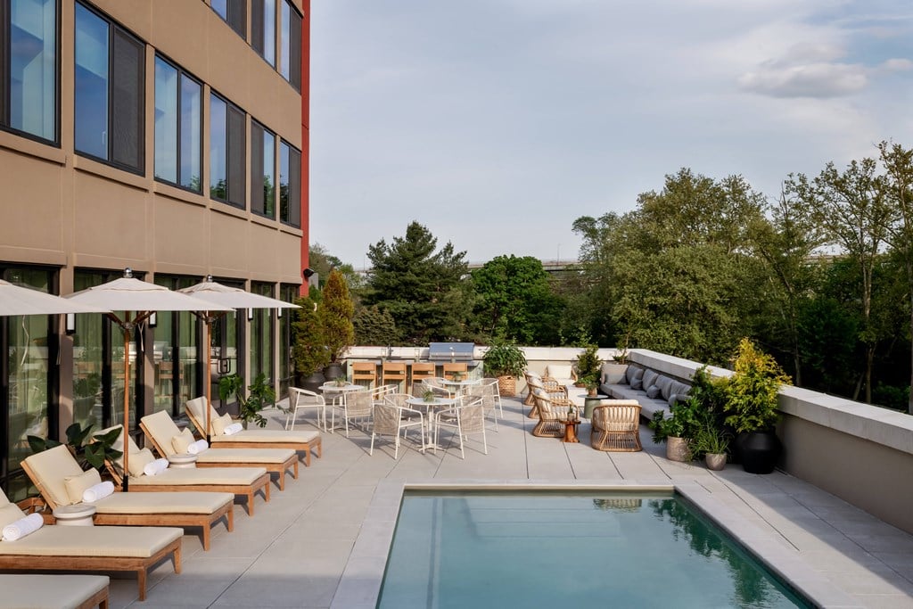 the pool and patio area of a hotel with chairs and umbrellas