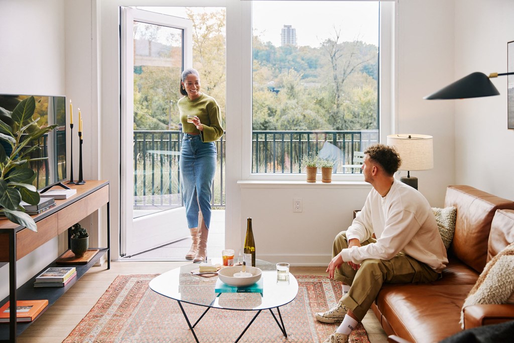 a man and a woman in a living room with a sliding glass door