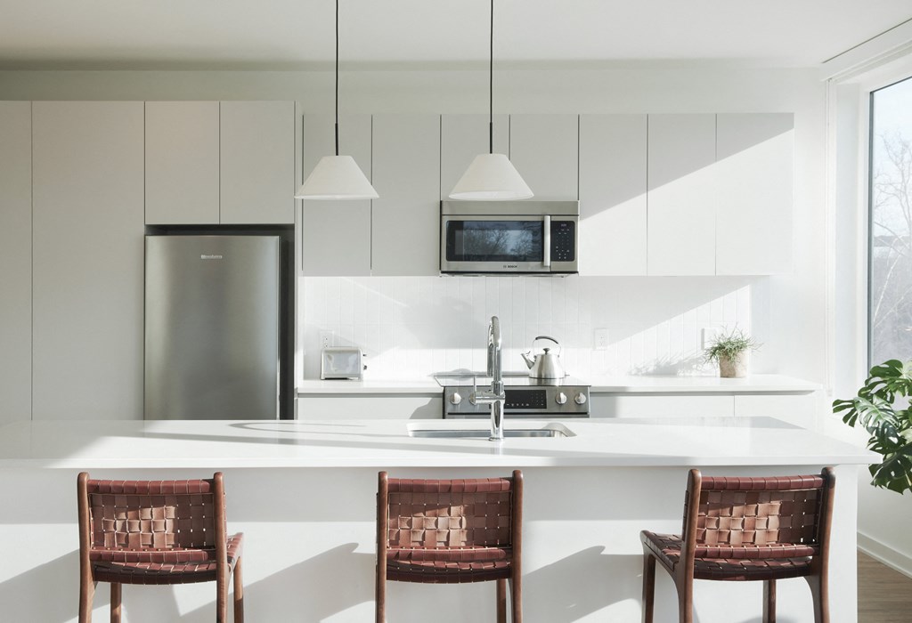 a modern kitchen with white cabinets and a white island with three chairs