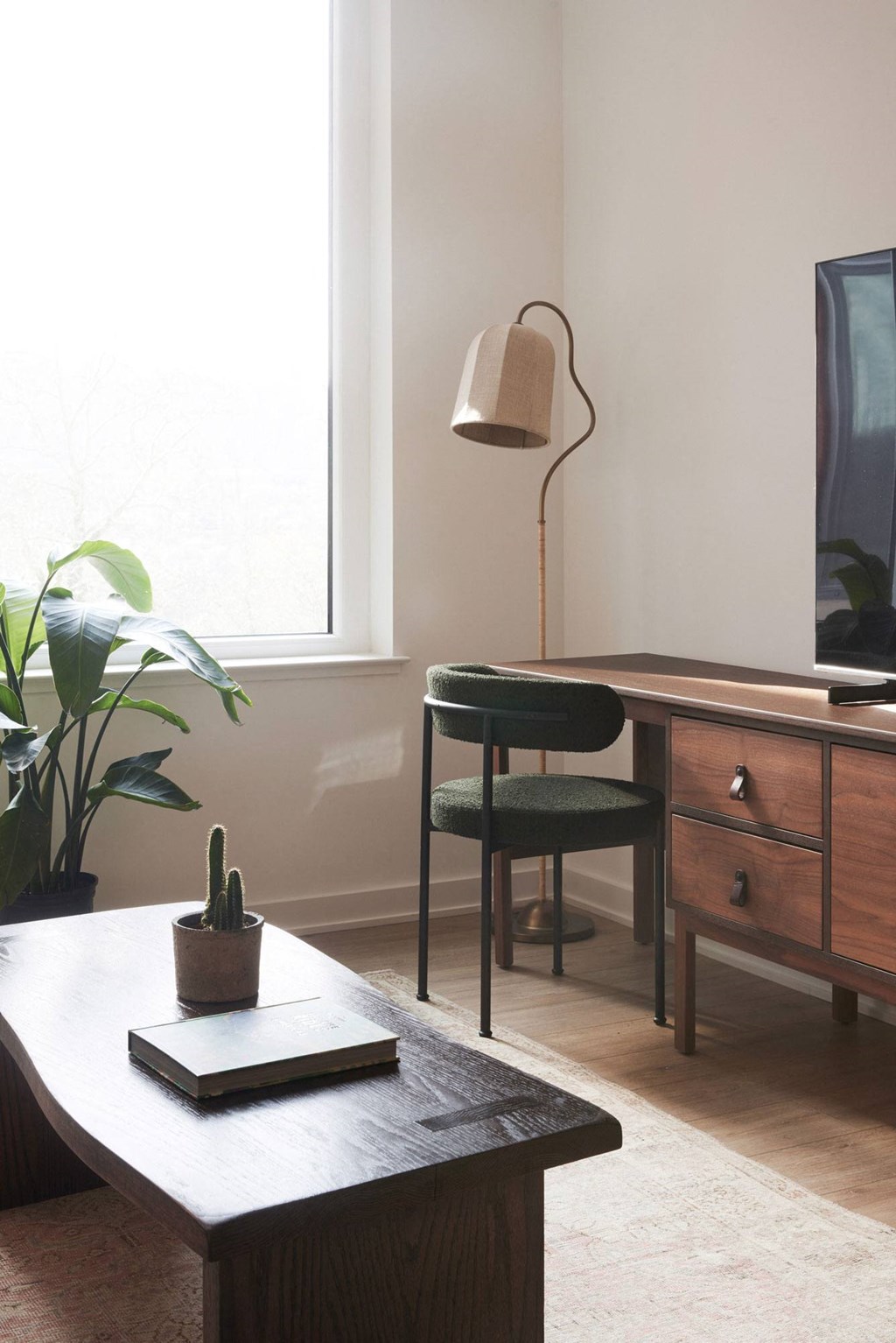 a living room with a desk and a chair and a lamp