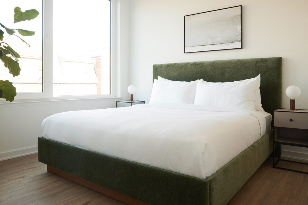 a bedroom with a bed with white sheets and a green couch