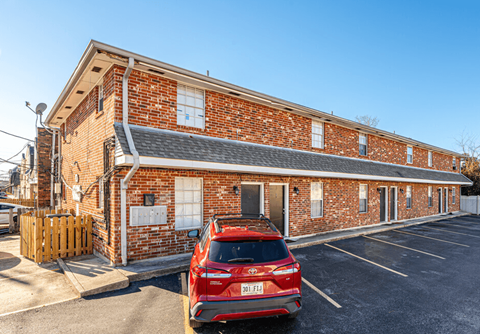 A red car is parked in front of a brick building.