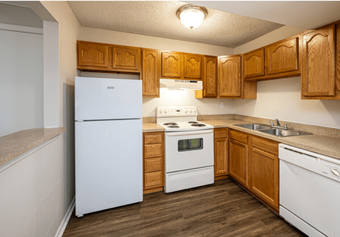 A kitchen with white appliances and wooden cabinets.