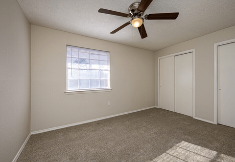 A room with a ceiling fan and a window with blinds.