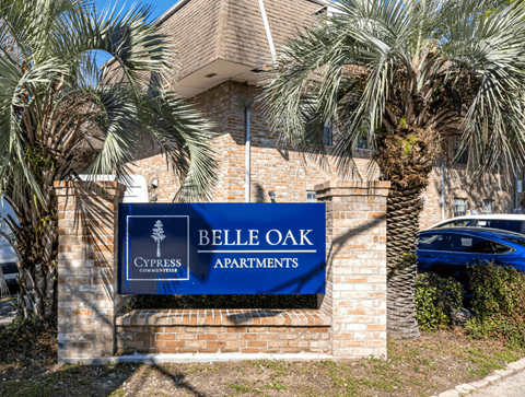 A sign for Belle Oak Apartments is displayed in front of a building.