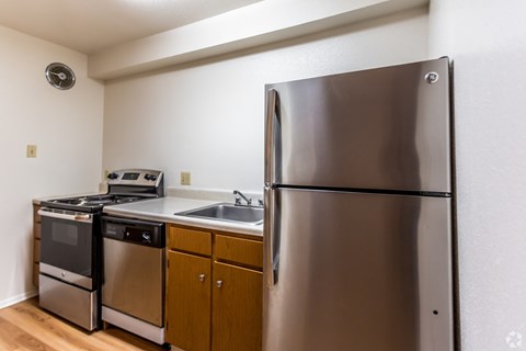 A kitchen with a stainless steel refrigerator, dishwasher, and oven.