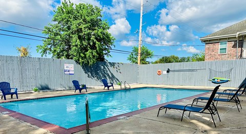A pool with blue water and chairs around it.