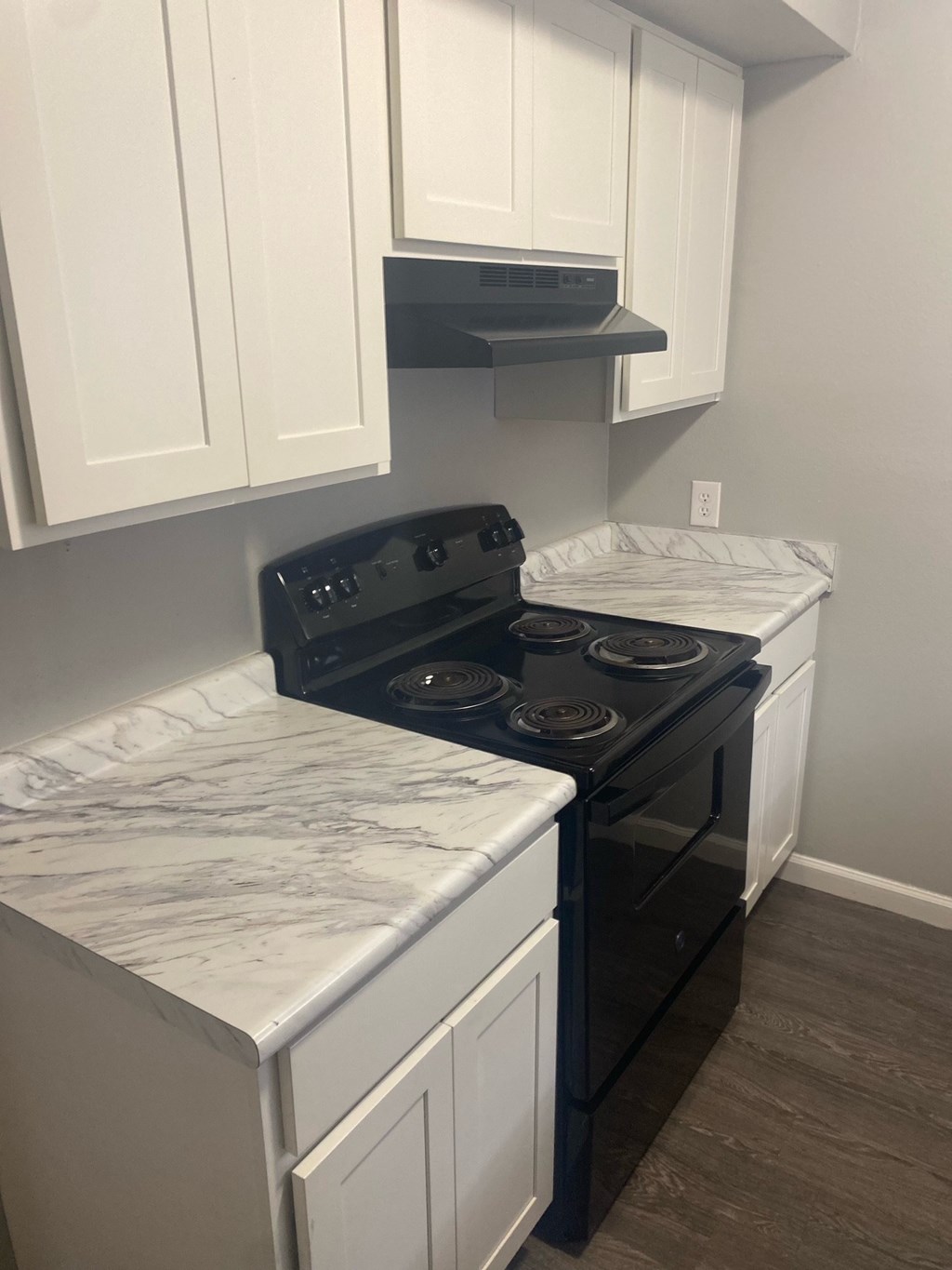 A kitchen with a black stove top oven and white cabinets.