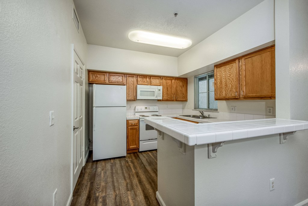 Wood plank floor with bar area refrigerator range over the range microwave dishwasher and kitchen window