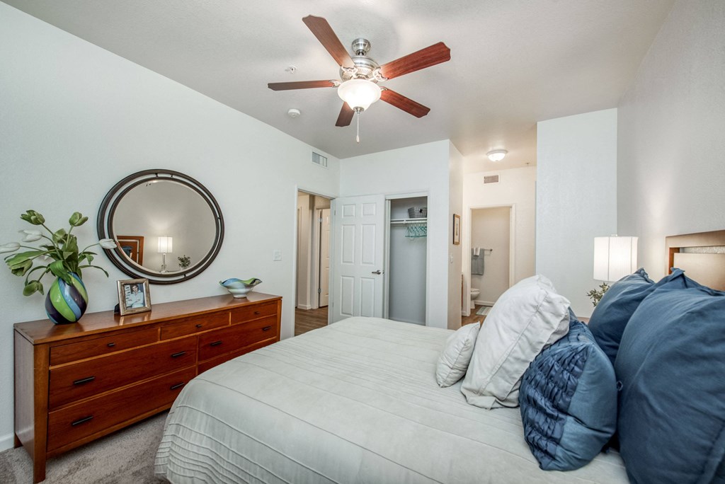 Large carpeted bedroom with 2 closets ceiling fan vanity area and enclosed toilet shower room