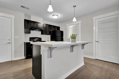 A kitchen with black cabinets and a white island.