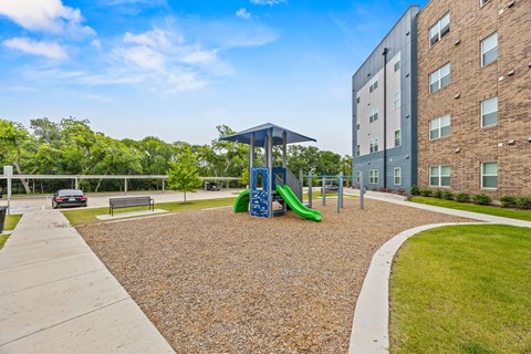 A playground with a blue slide and a green slide in front of a building.