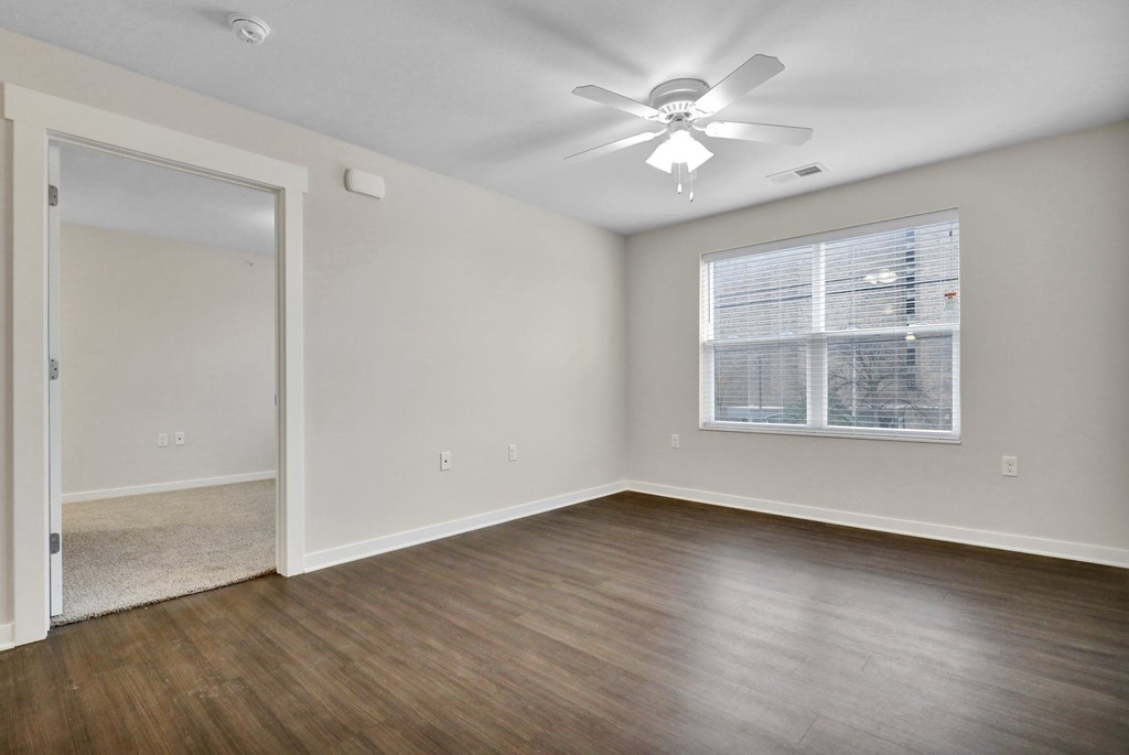 A room with a ceiling fan and a window with blinds.