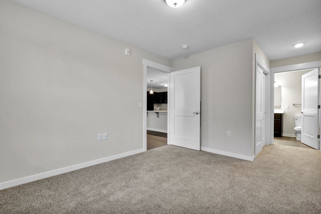 A spacious room with white walls and a carpeted floor.