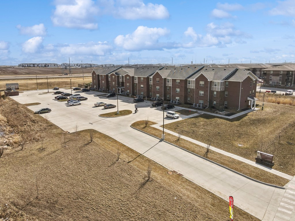 Apartment complex with a parking lot in front.