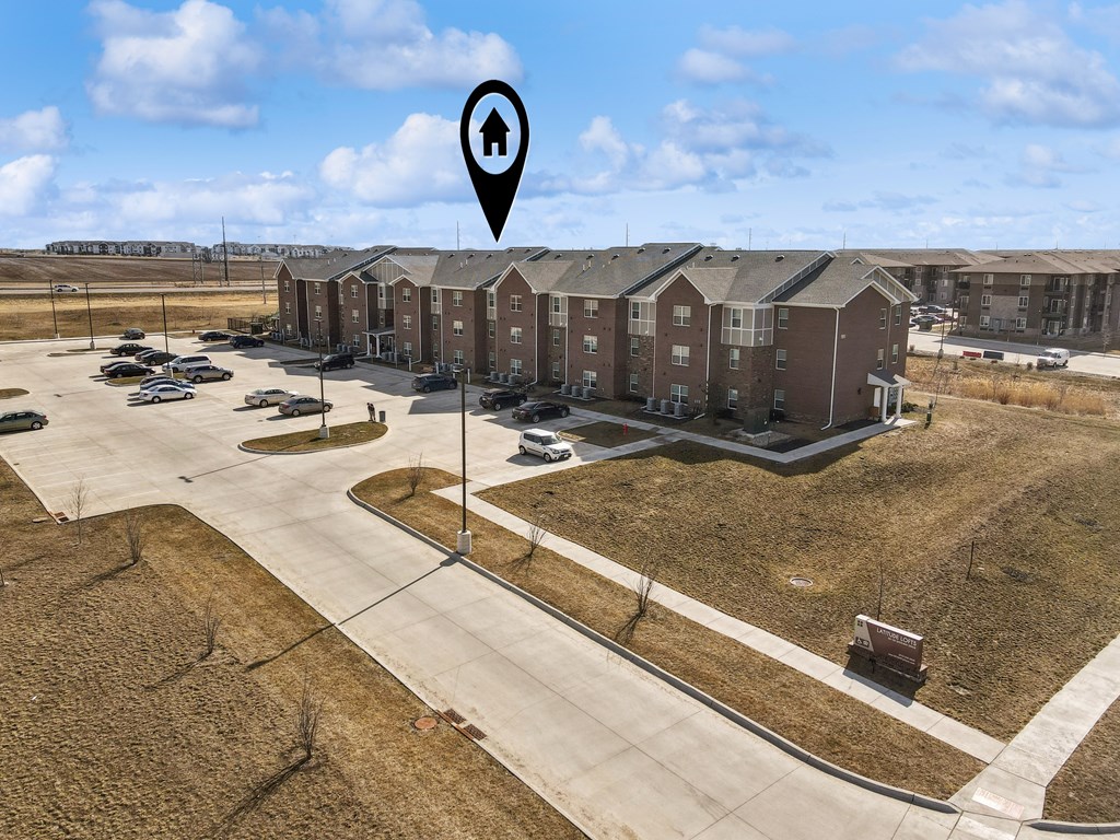 A large apartment complex with a parking lot in front.