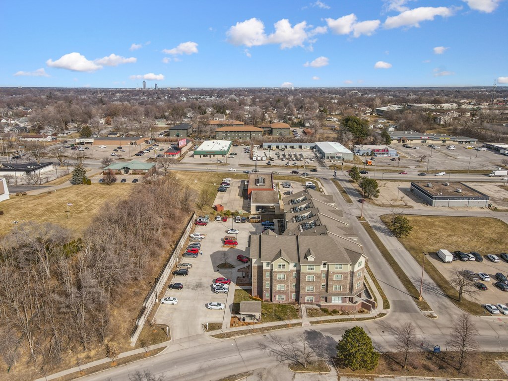A large parking lot is surrounded by buildings and trees.