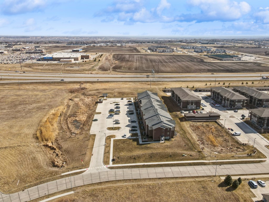 A large open field with a small building and a parking lot in the foreground.