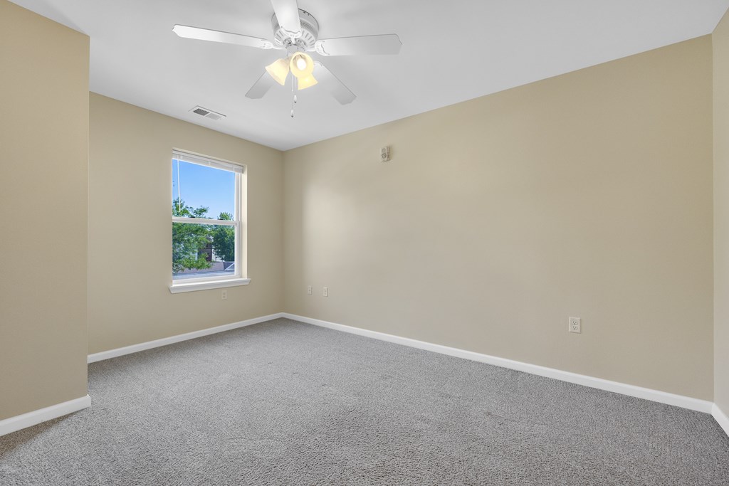 A room with a ceiling fan and carpeted floor.