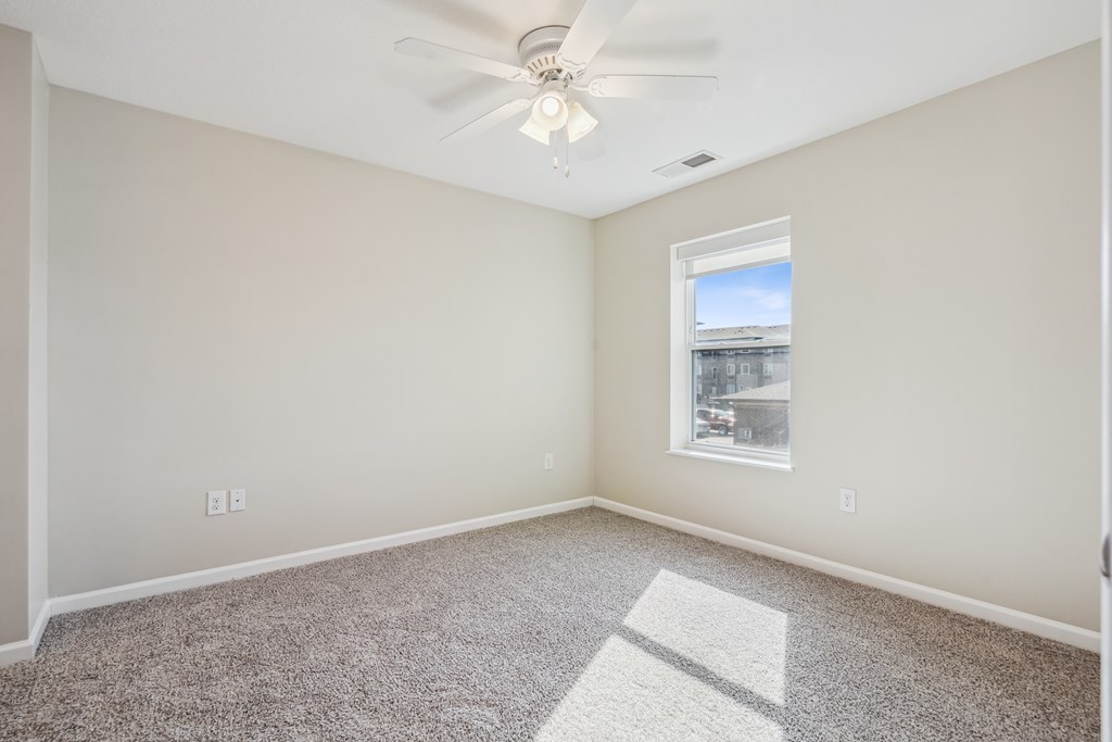 A room with a ceiling fan and a window letting in light.