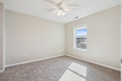 A room with a ceiling fan and a window letting in light.
