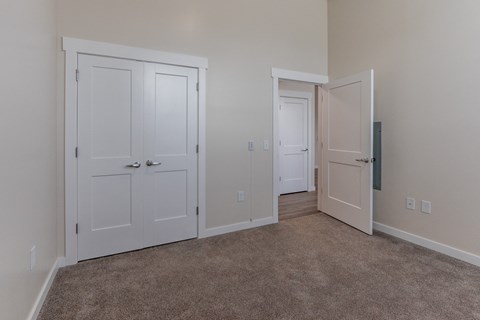 an empty bedroom with two doors and a carpeted floor