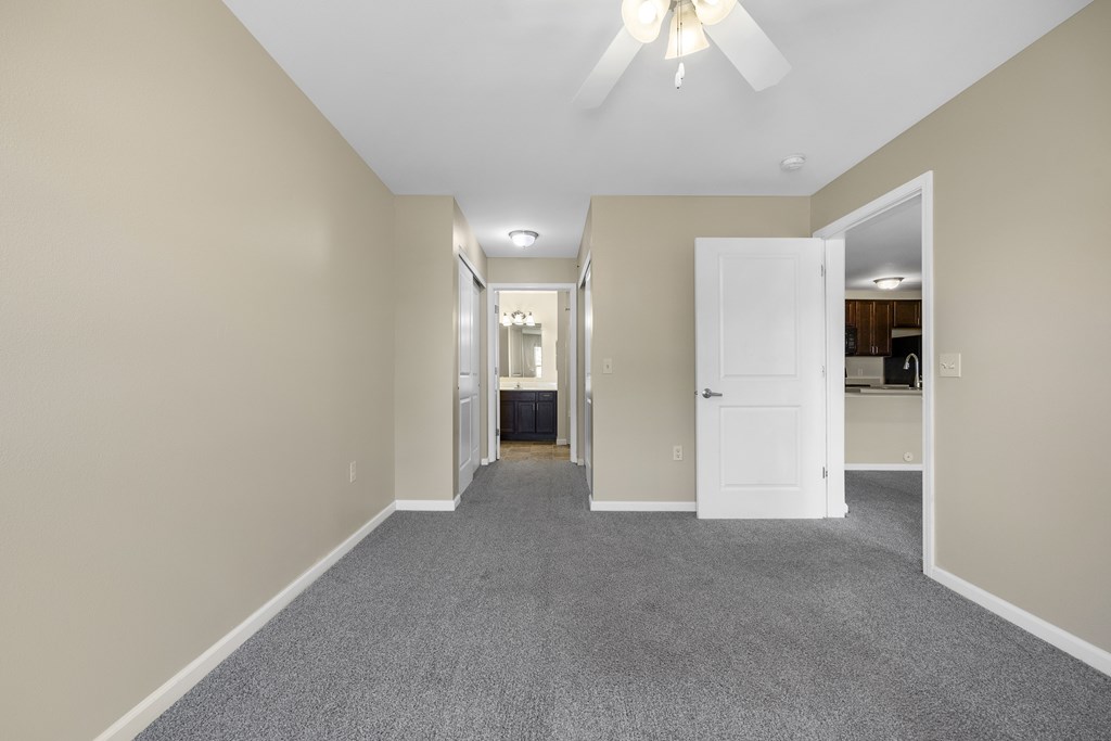 A long hallway with a carpeted floor and a ceiling fan.