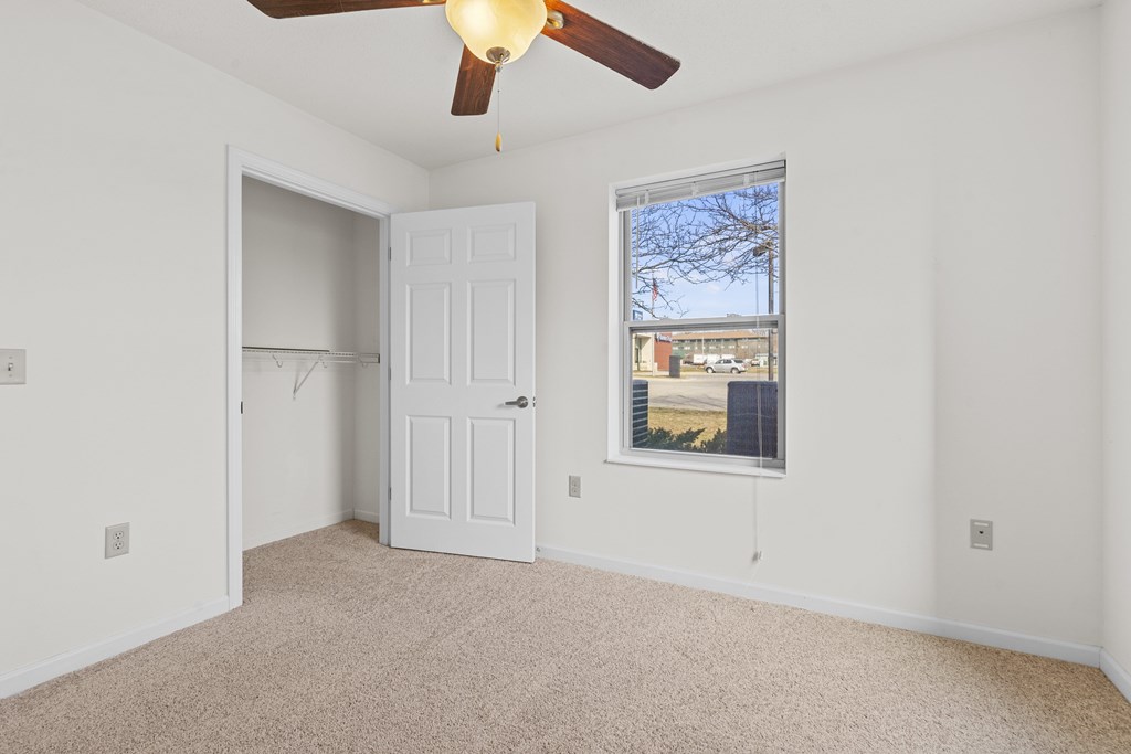 A room with a ceiling fan and a window overlooking a cityscape.