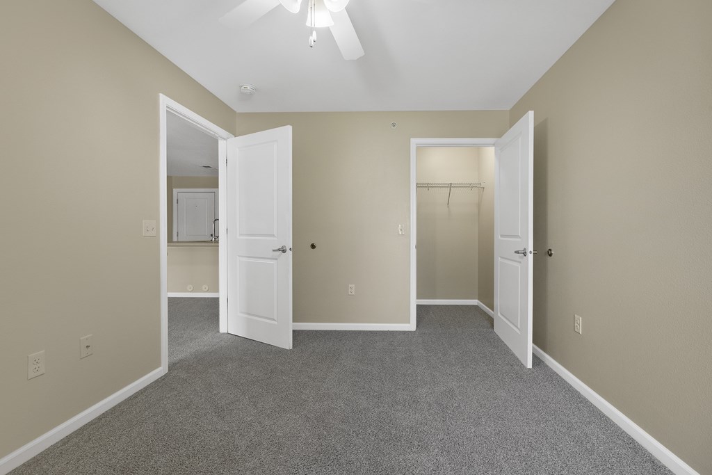 A room with a carpeted floor and two open doors.