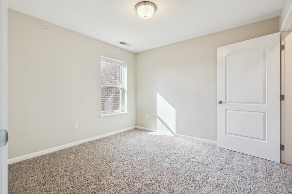 A room with a carpeted floor and a window with blinds.