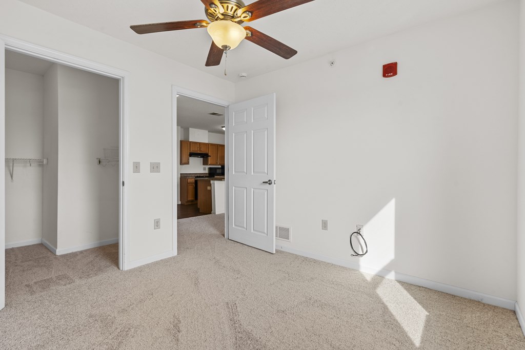 A room with a ceiling fan and carpeted floor.