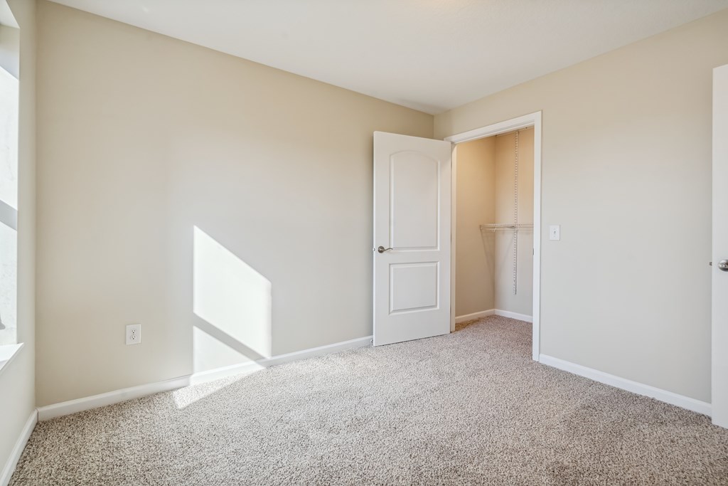 A room with a carpeted floor and a white door.