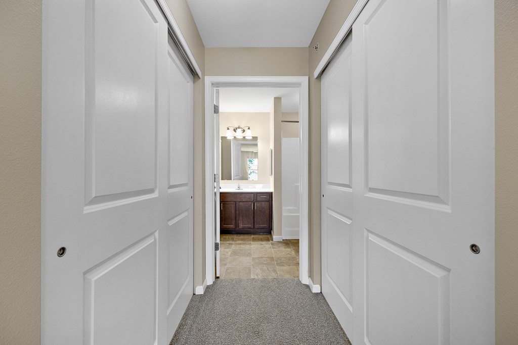 A hallway with white doors and a carpeted floor.