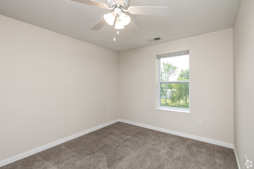 A room with a ceiling fan and carpeted floor.