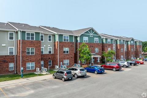 A parking lot with cars and apartment buildings in the background.