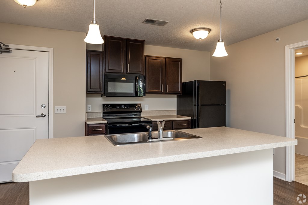 A kitchen with a white countertop and dark brown cabinets.