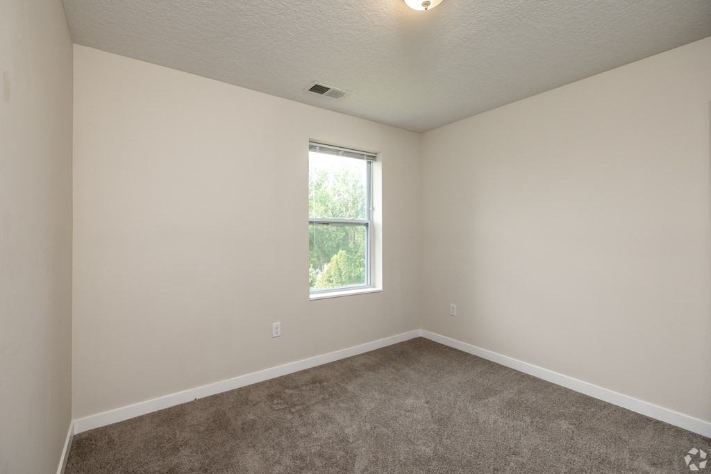 A room with a carpeted floor and a window.