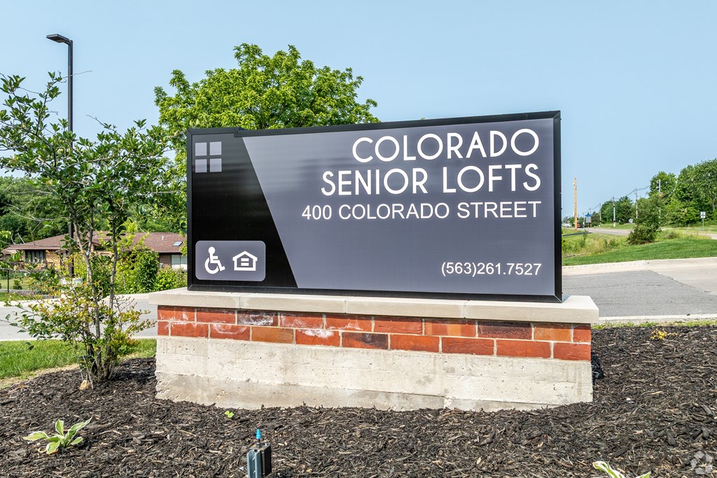 A sign for Colorado Senior Lofts is displayed in front of a building.