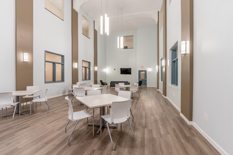 a dining room with white tables and chairs and a wood floor