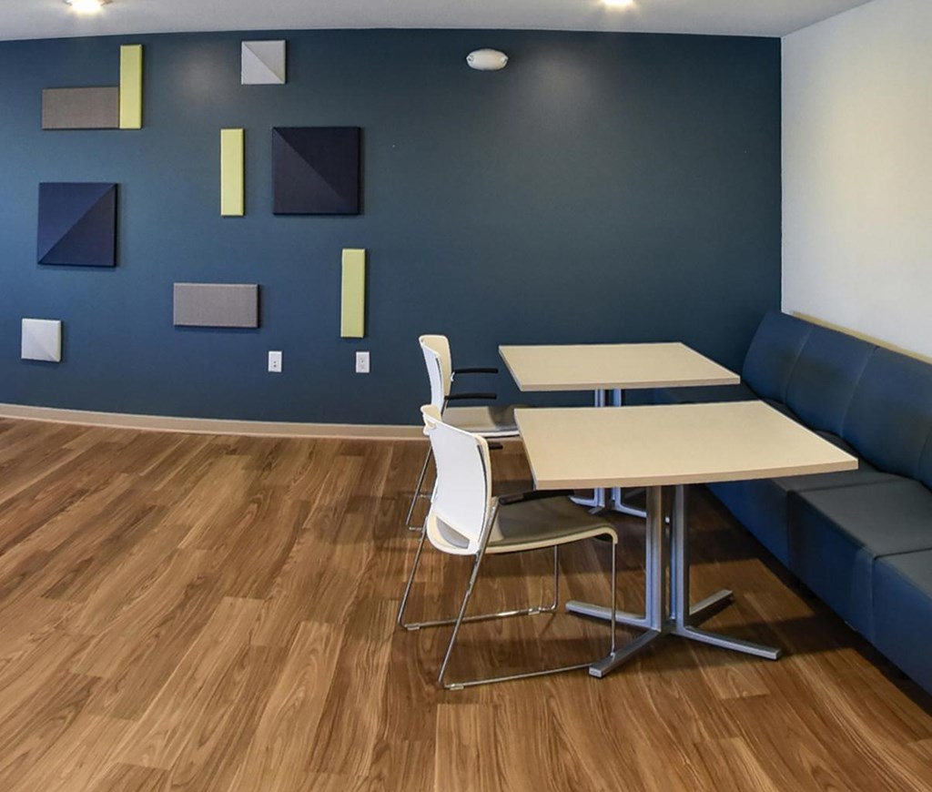 A room with a blue wall and a white table and chairs.
