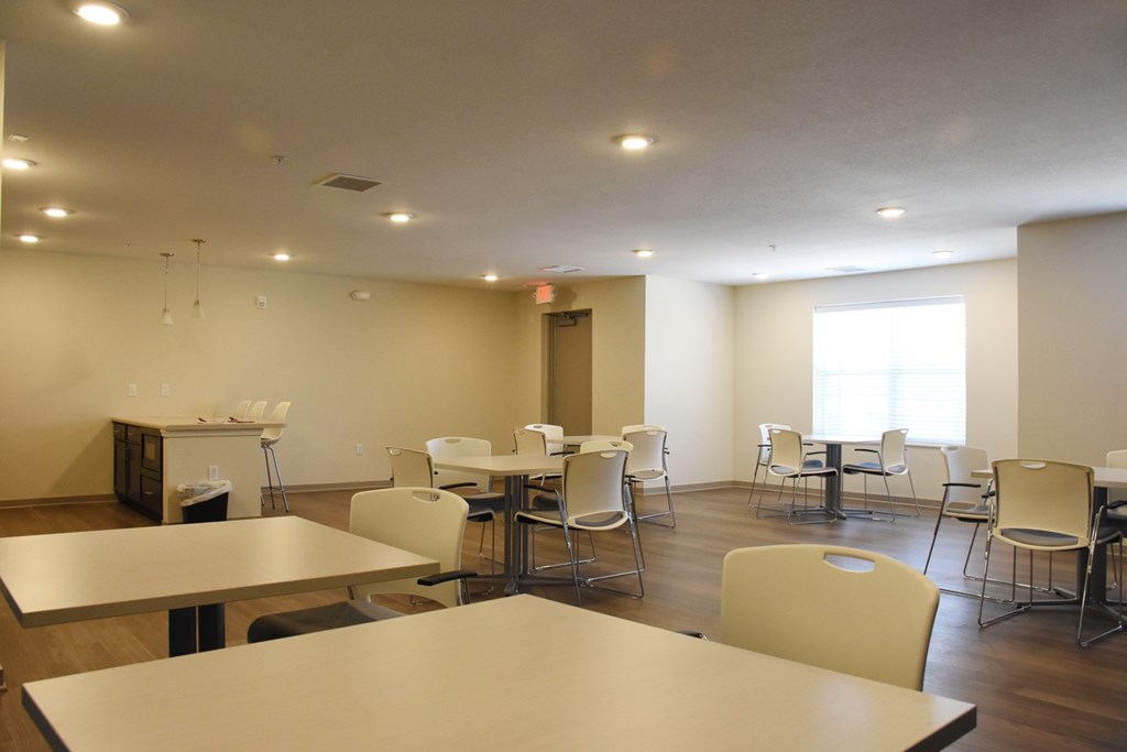 A room with tables and chairs and a window.